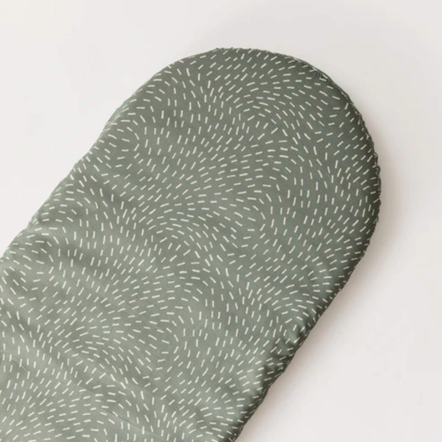 Oval-shaped fitted sheet in sage green Dashes print laid flat to show overall pattern and shape.