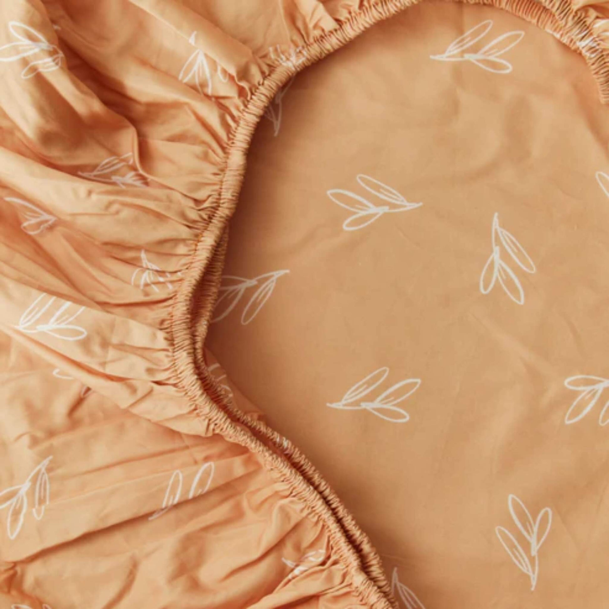 A detailed view of gathered elastic seams on a fitted sheet, highlighting stretch and secure construction around a mattress edge.