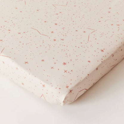 Kabode Starscape fitted cot sheet in cream organic cotton with a soft pink star and constellation print, shown neatly fitted over a mattress corner.