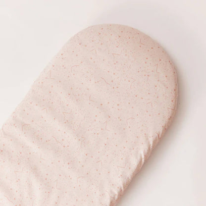 Top-down view of an oval mattress fitted with a cream cotton sheet patterned with small pink stars and constellation markings.