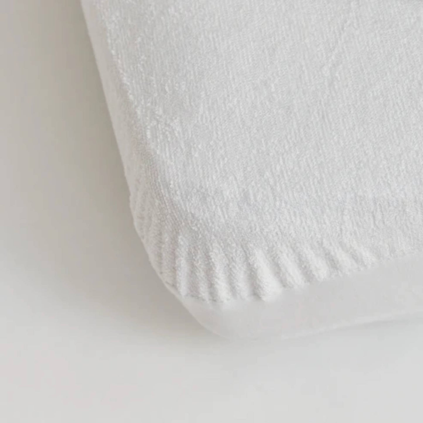 Kabode bamboo waterproof mattress protector fitted sheet in soft white fabric, shown close up on a mattress corner with elasticated edge for a secure snug fit.