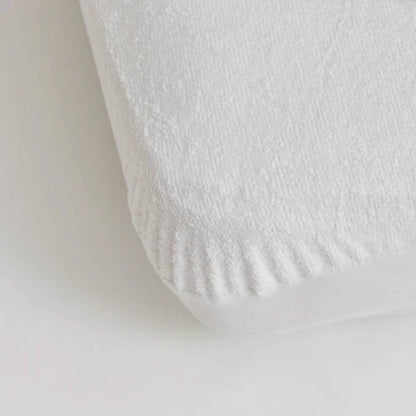 Kabode bamboo waterproof mattress protector fitted sheet in soft white fabric, shown close up on a mattress corner with elasticated edge for a secure snug fit.