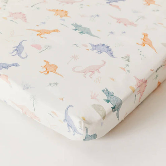 Kabode Organic Cotton Fitted Sheet with a soft cream base and a playful dinosaur print in muted pastel tones, shown neatly fitted over a mattress with elasticated edges.
