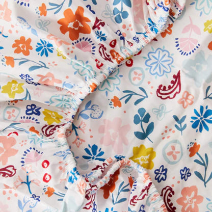 A close-up view of organic cotton fabric gathered at the elasticated edge, showing the smooth weave and detailed floral illustrations.