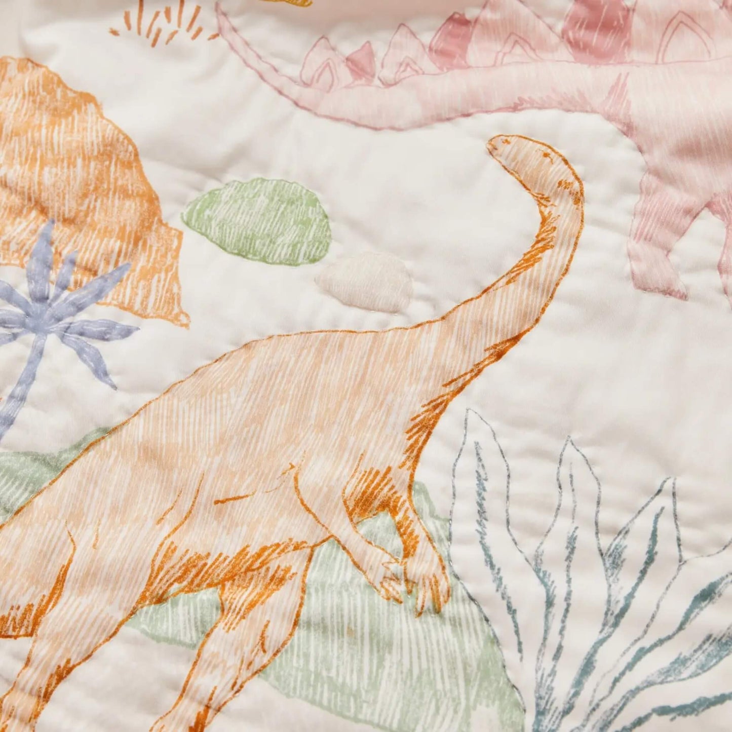 A detailed view of dinosaur figures printed on quilted cotton, showing sketch-style outlines, pastel colouring, and gentle texture in the fabric.