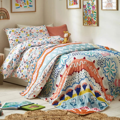 A child’s single bed styled with a floral quilt layered over matching bedding, featuring bold curved patterns, scattered floral shapes, and soft contrasting colours.