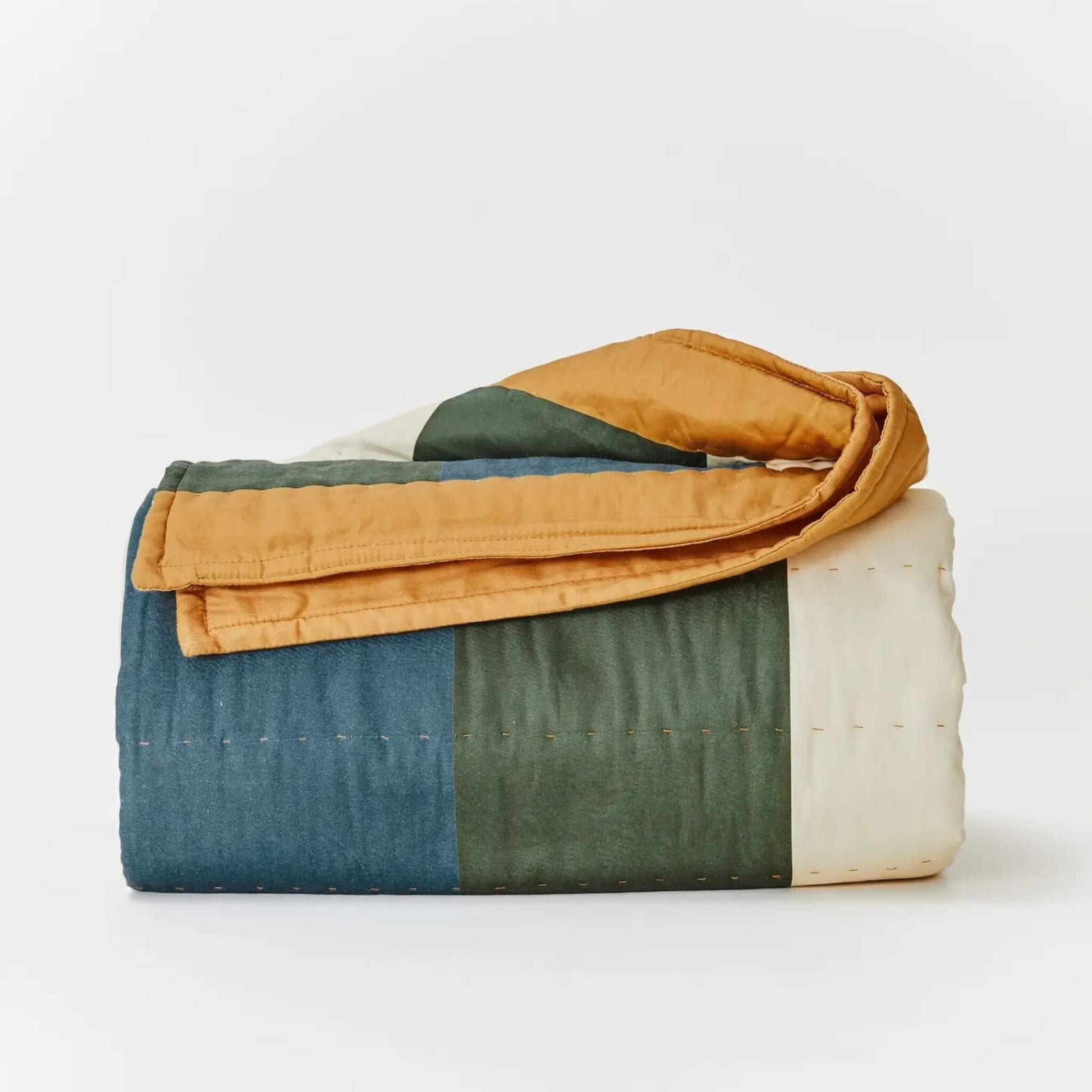 Kabode Organic Cotton Quilt  shown with striped design folded to show wide vertical bands in deep blue, forest green, soft cream, and a warm ochre edge with stitched detailing.