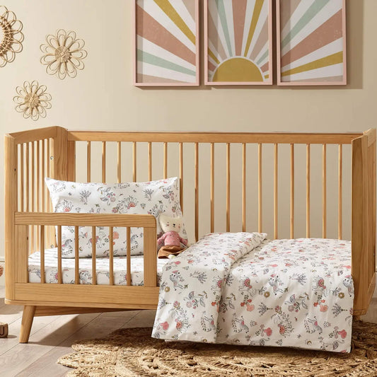 Boho print Kabode cot bed duvet cover and pillowcase set folded neatly with the matching pillowcase on top, shown in soft cream organic cotton printed with delicate florals, animals, and hand-drawn details.