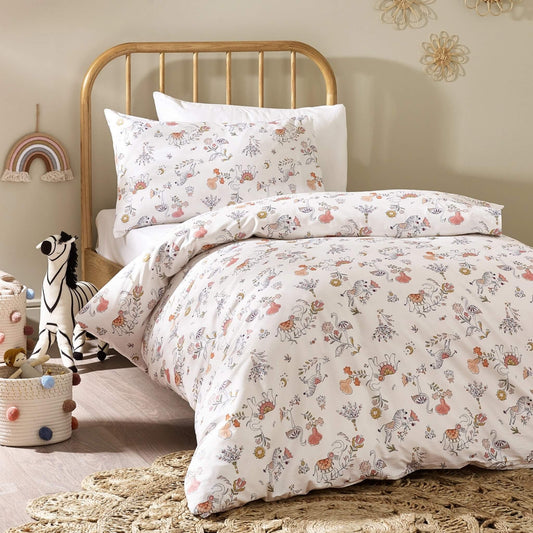 A child's single bed dressed in a cream duvet cover and pillowcase featuring soft floral motifs and playful animal drawings, paired with a wooden headboard and neutral bedroom decor.