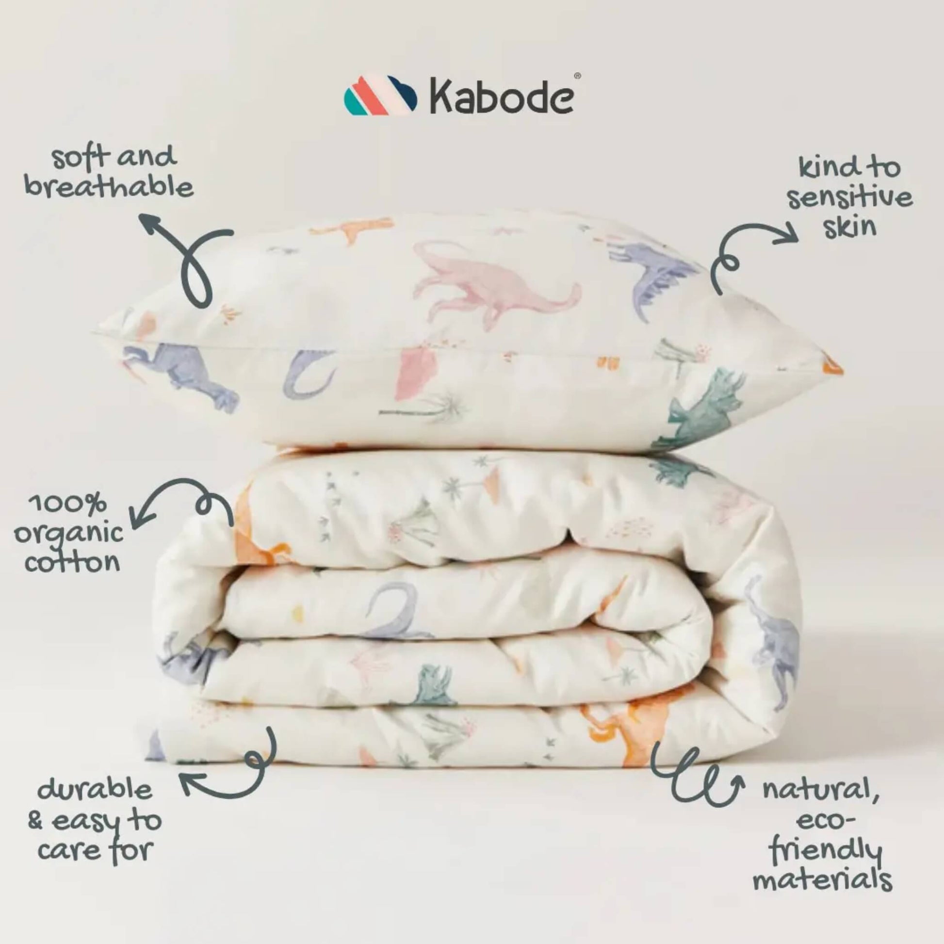Folded duvet and pillow stacked together, showing cream organic cotton printed with scattered dinosaur illustrations and fine hand-drawn details.