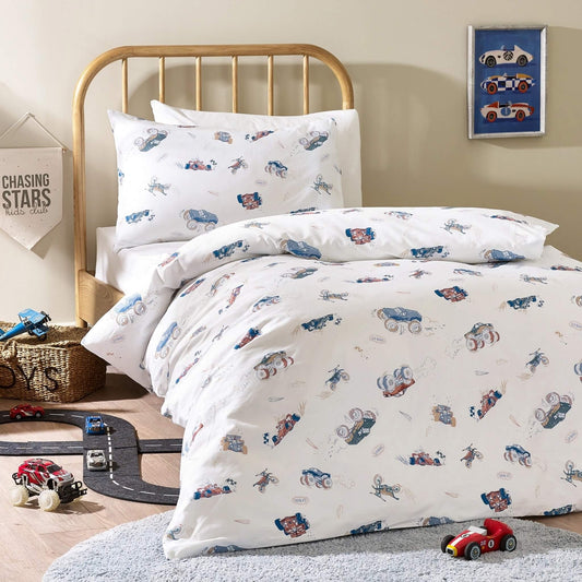 A single bed styled with a duvet cover and pillowcase printed with hand drawn vehicles including racing cars, monster trucks, and motorbikes on a light cream background.