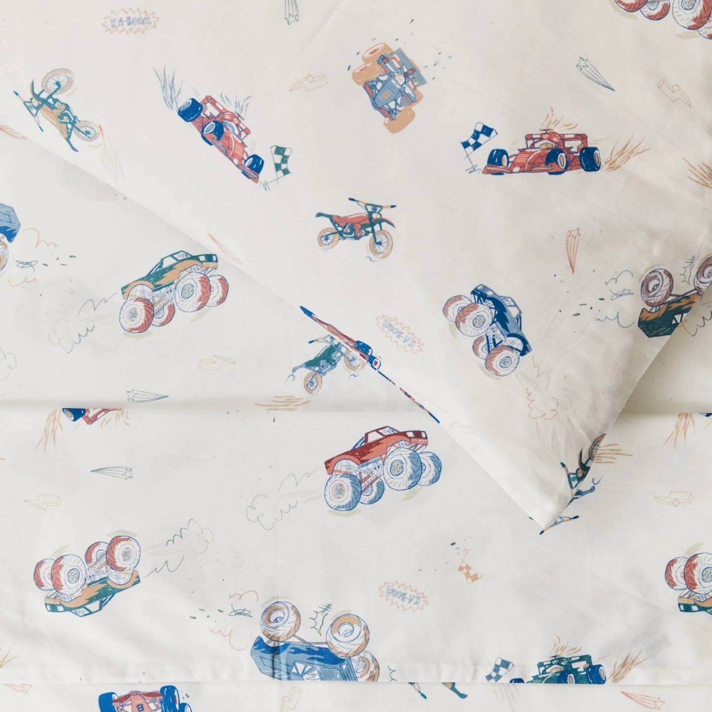 Detailed close up of duvet cover fabric showing illustrated cars, trucks, motorbikes, flags, and sketched motion marks printed on smooth cream cotton.