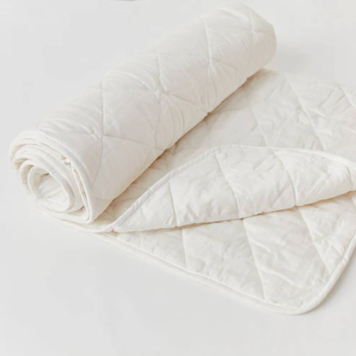 Kabode toddler wool duvet folded and rolled, showing quilted organic cotton outer and soft natural wool filling on a light background.
