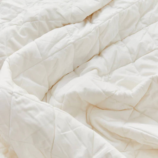 Close-up of quilted cream duvet fabric with stitched square pattern, showing soft padding and breathable cotton texture.