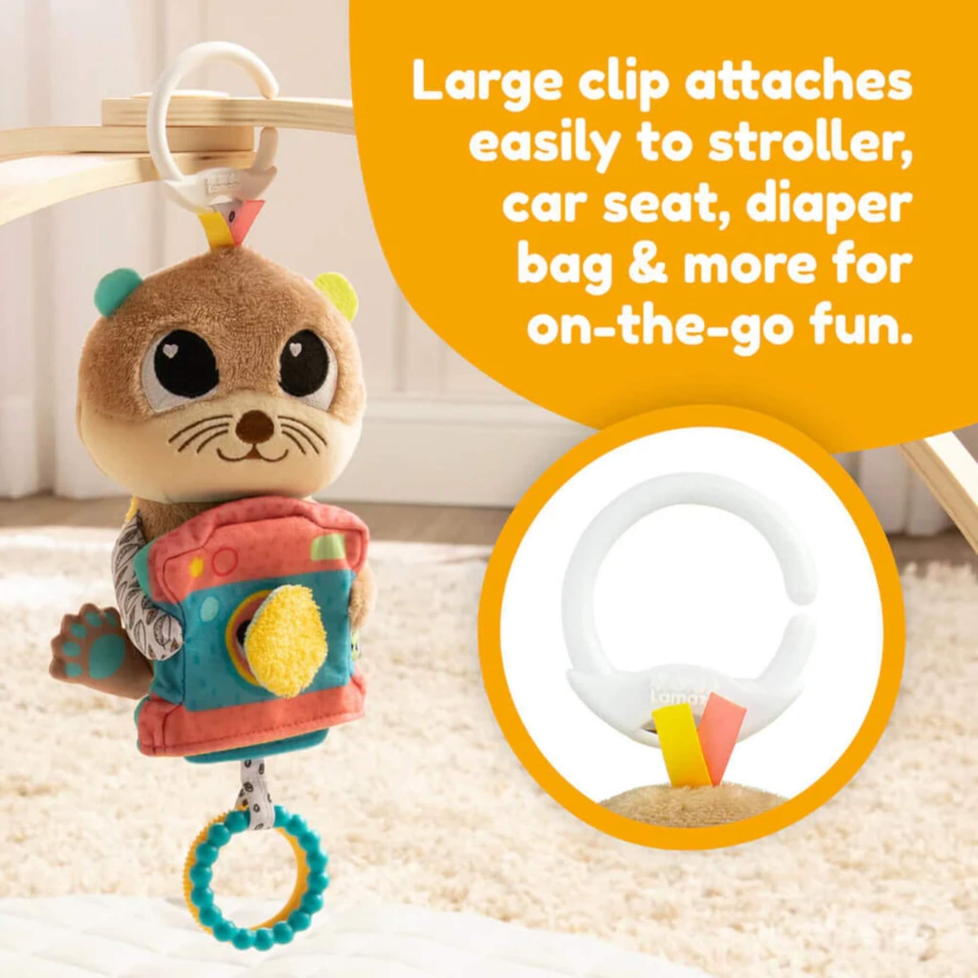 Plush otter toy hanging from a light wooden play arch with a white clip attachment, suspended over a soft cream play mat.