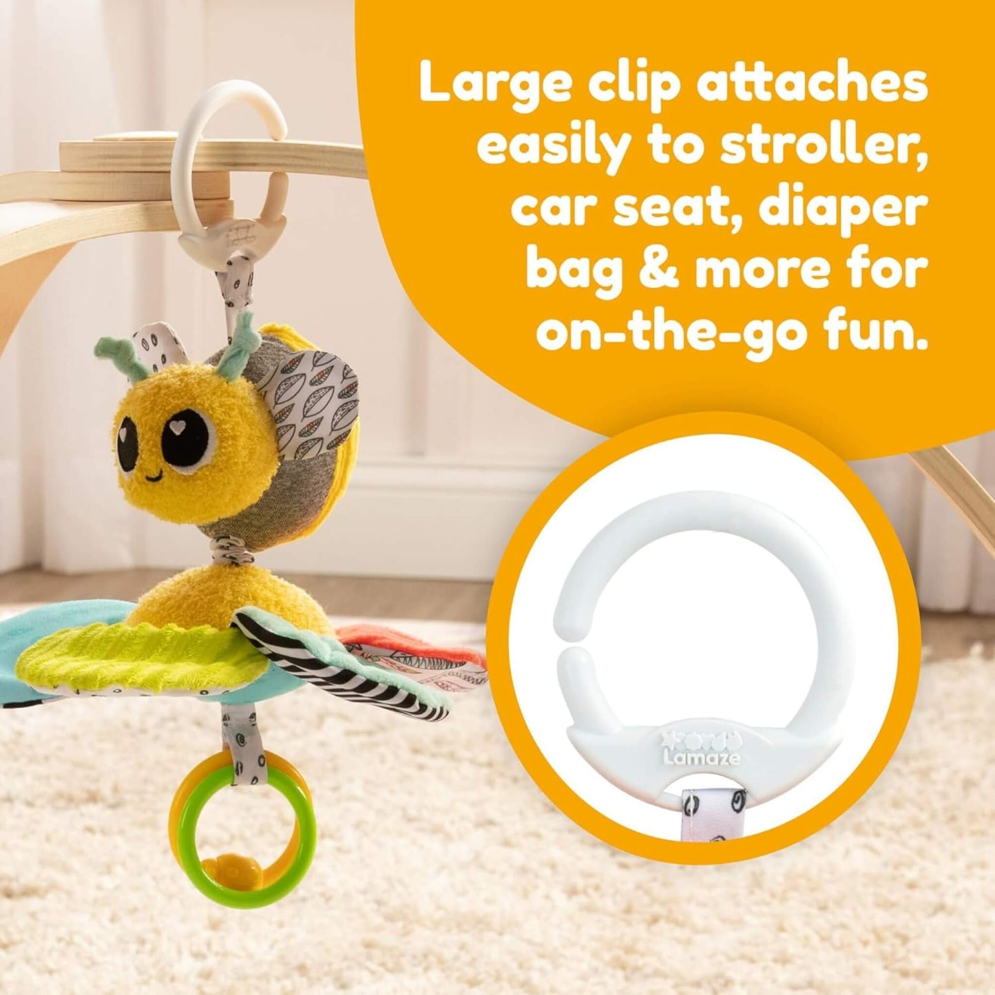 Plush bee toy hanging from a wooden table with a white Lamaze clip, showing text about on-the-go use.
