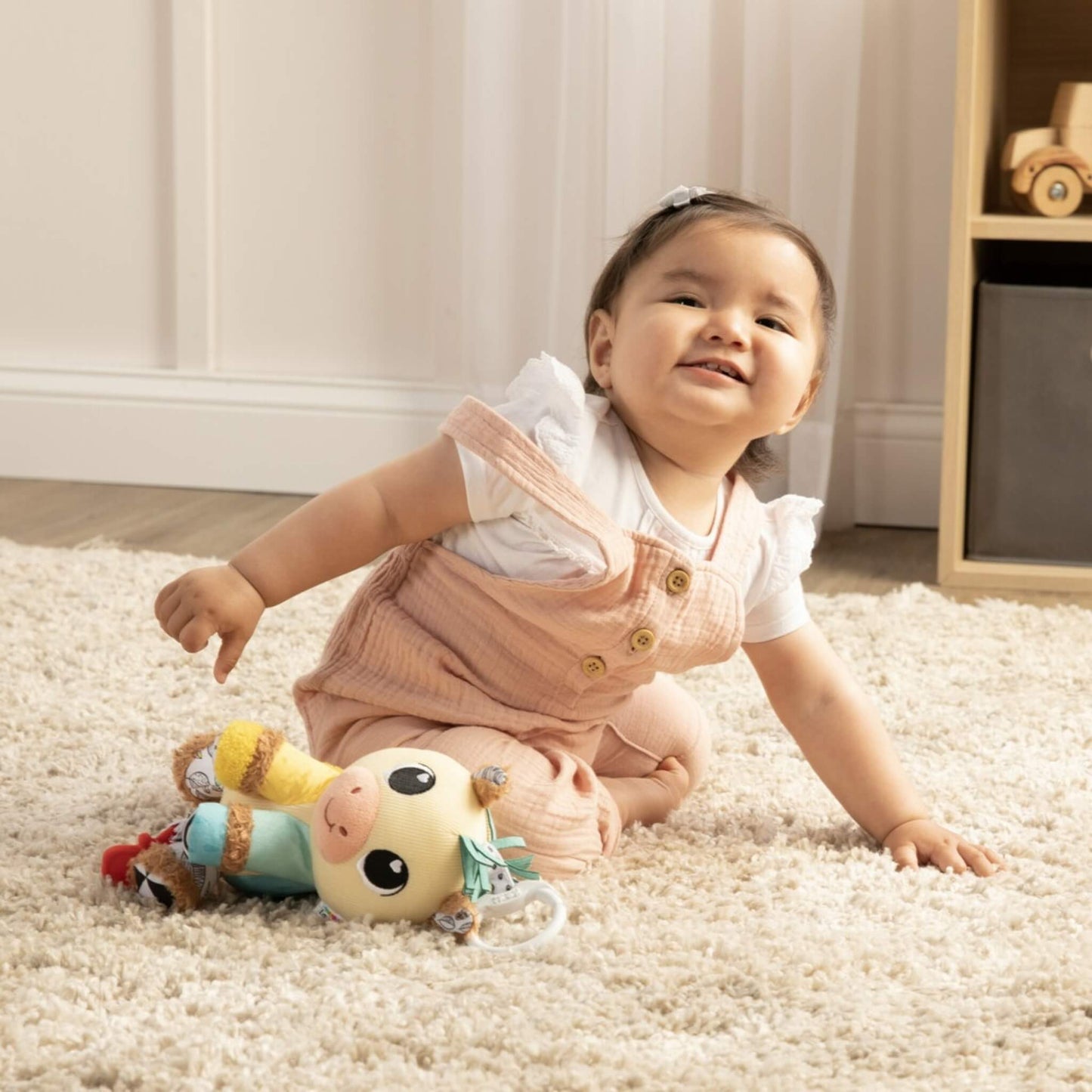 Baby playing on carpet with plush horse toy, exploring its bright textures and teether.