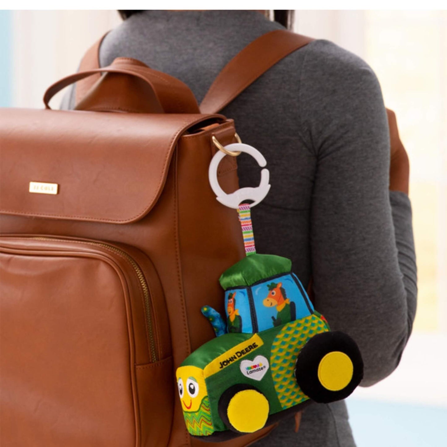 Toy clipped to a tan leather changing bag, showing portable design for travel or outings.
