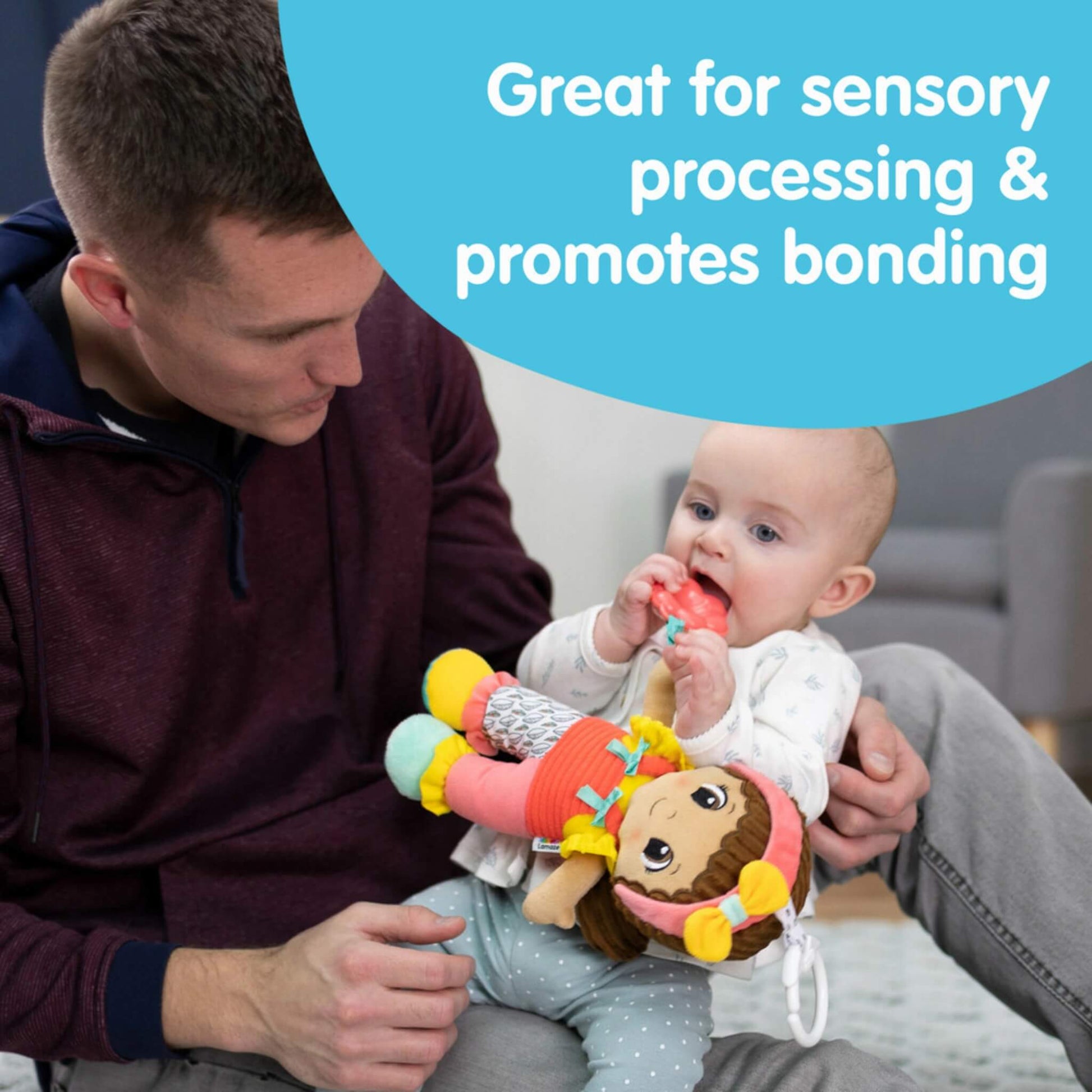 Father sitting with baby on his lap, helping the baby grasp a Lamaze doll while text on the image highlights sensory processing and bonding benefits.