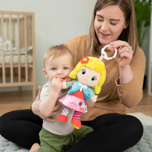 Mother sitting on the floor holding baby on her lap while showing a soft doll with bright yellow hair and colourful outfit.