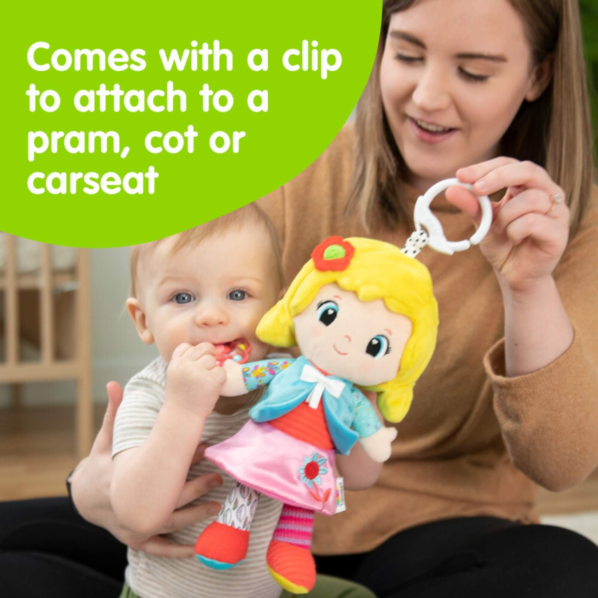 Parent holding a colourful soft doll with a white clip, showing how it can attach easily to a pram, cot or car seat for travel and play.