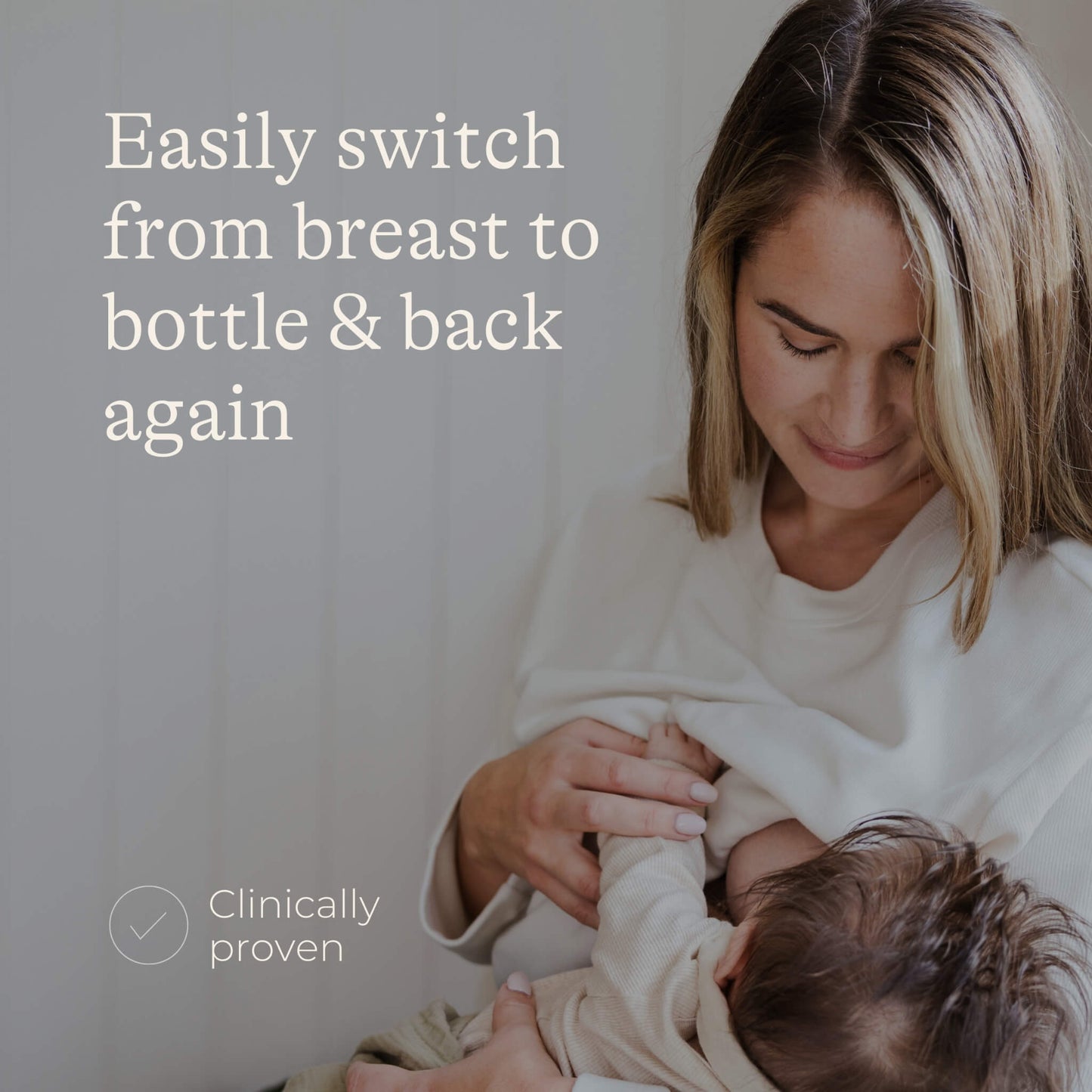 Mother breastfeeding a baby while seated indoors, showing a natural feeding position and close parent-baby interaction.