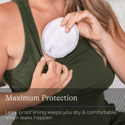 Pregnant woman fitting a disposable breast pad into her nursing bra for a secure, non-slip fit.