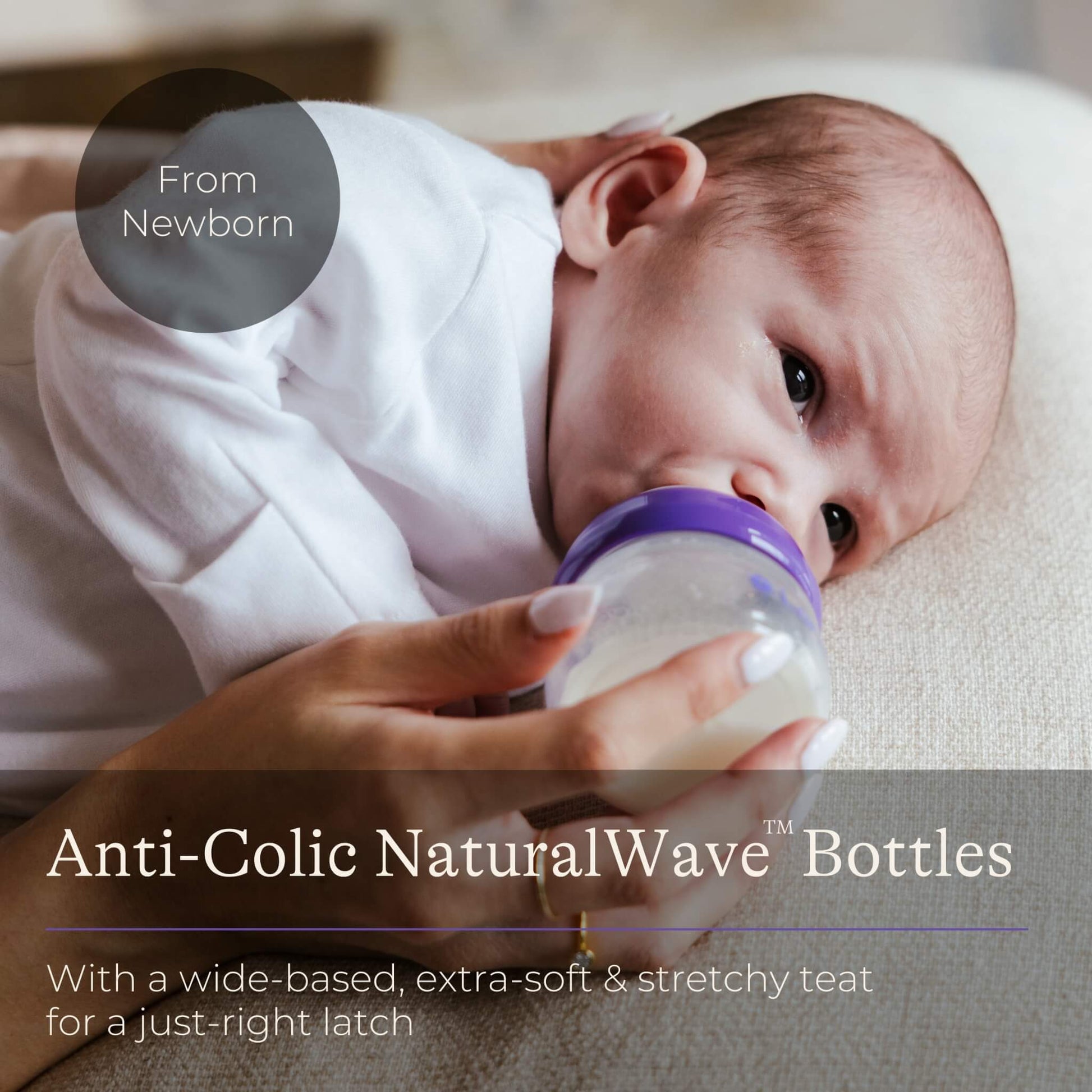 Newborn baby lying on a soft surface while being fed from a small feeding bottle held by an adult.