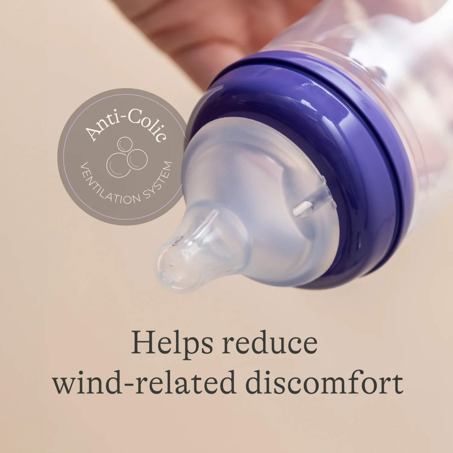 A detailed view of a clear silicone bottle teat with a purple collar, highlighting an anti-colic ventilation system designed to help reduce wind-related discomfort.