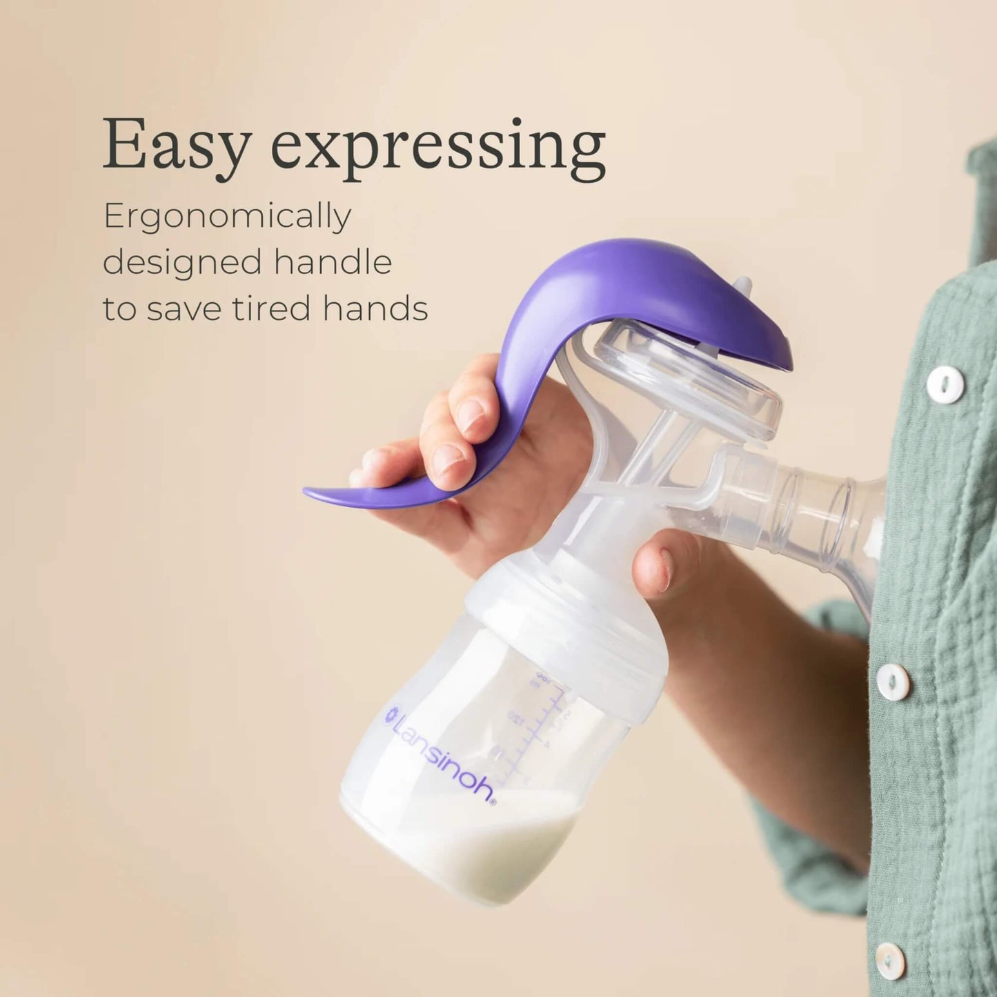 Close-up of hand operating the Lansinoh manual breast pump handle with expressed milk in the bottle, highlighting ergonomic grip and easy control.