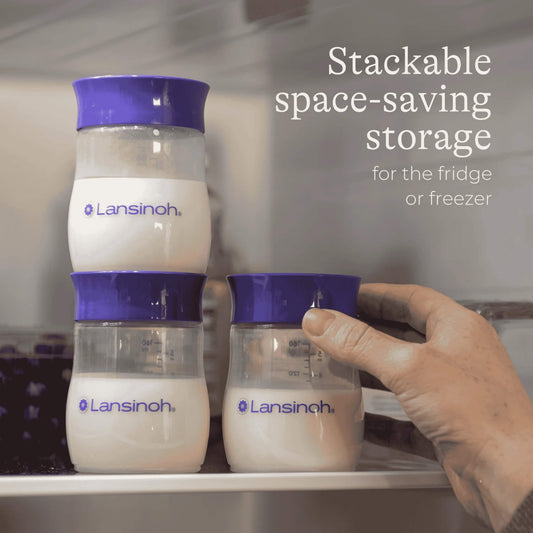 Three breastmilk storage bottles filled with milk arranged inside a fridge, with one bottle stacked on top of another and a hand placing an additional bottle onto the shelf.