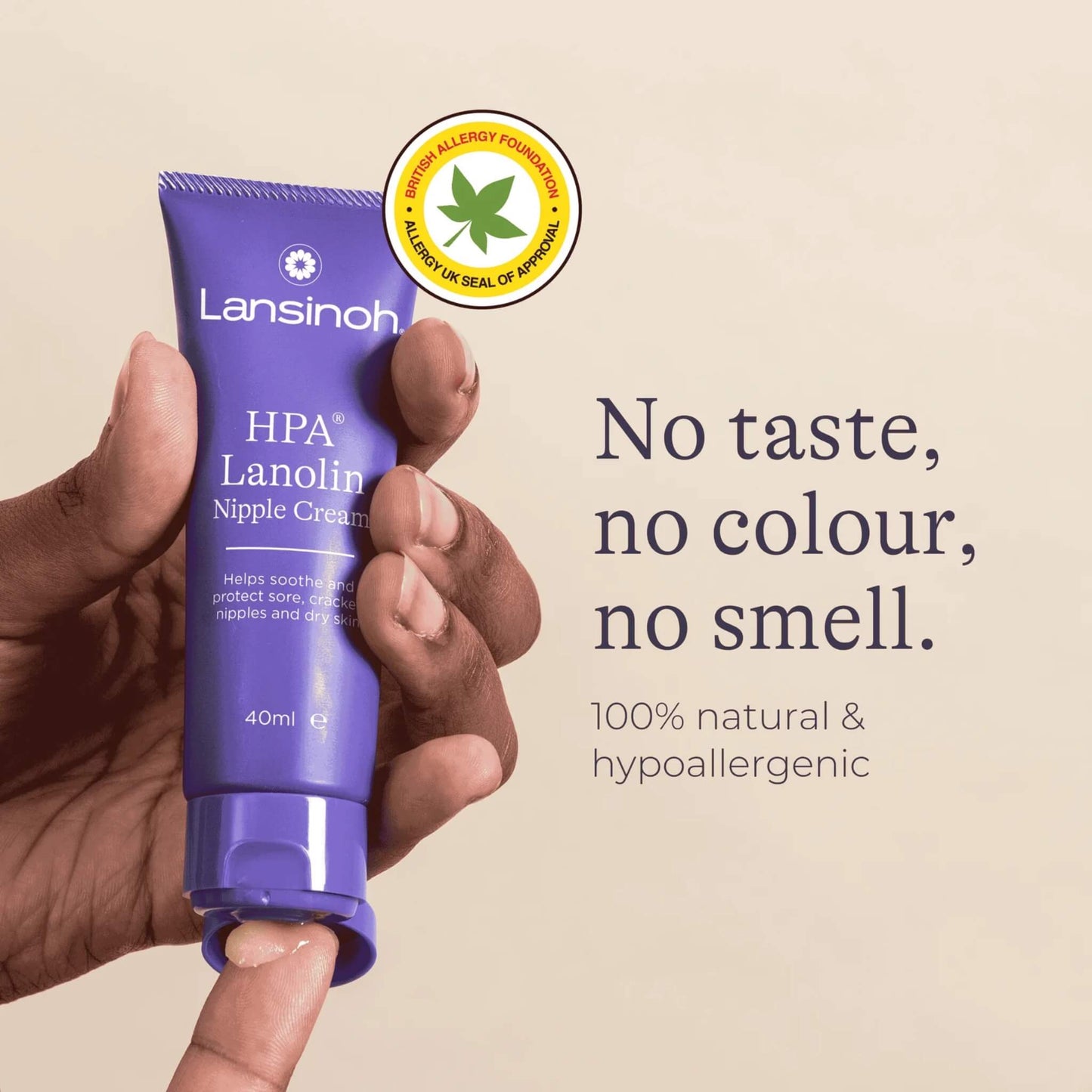 Close-up of a hand holding an open tube of nipple cream with a small amount of cream dispensed onto a fingertip.