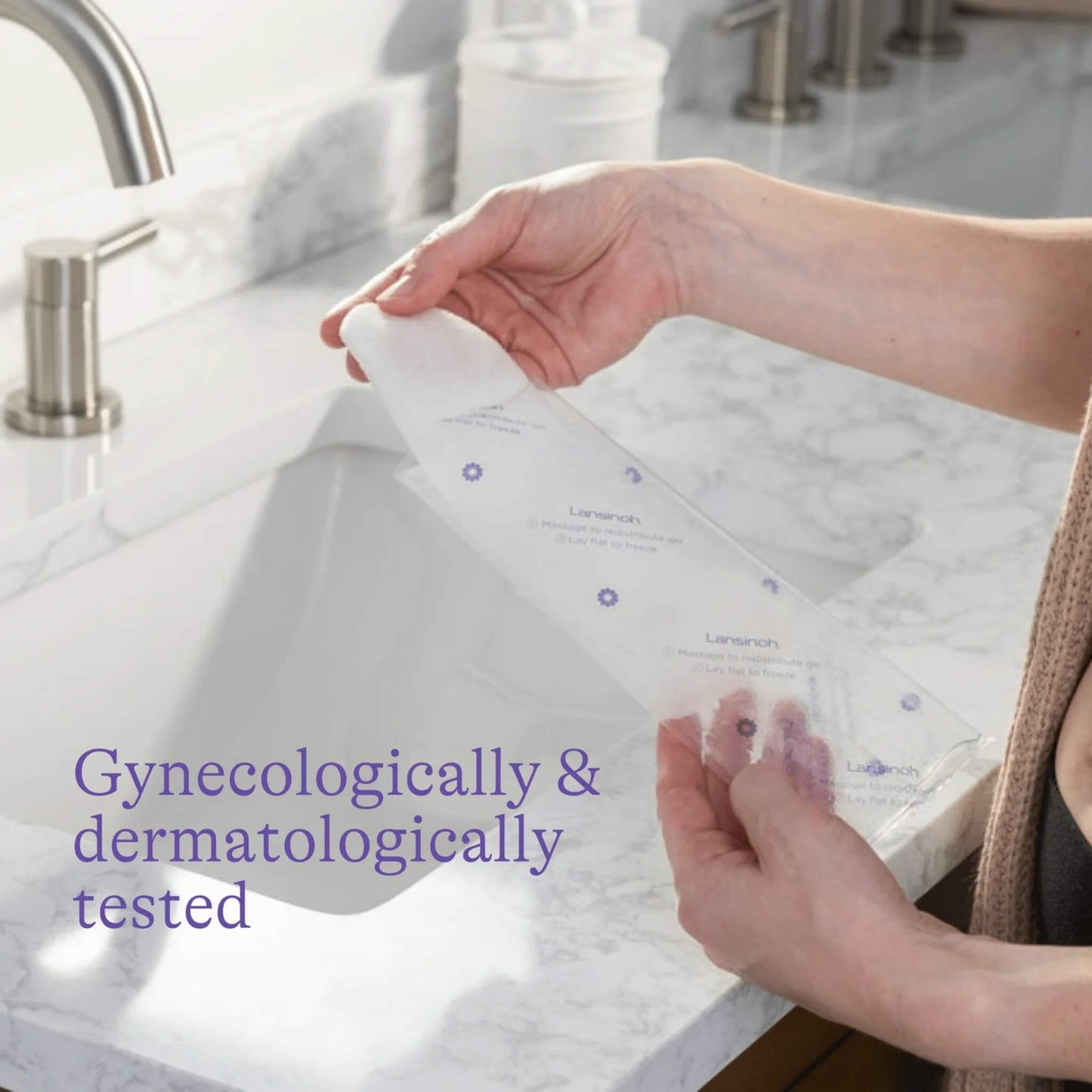 A woman holding a postpartum padsicle beside a bathroom sink, showing the individually wrapped pad that is gynaecologically and dermatologically tested.