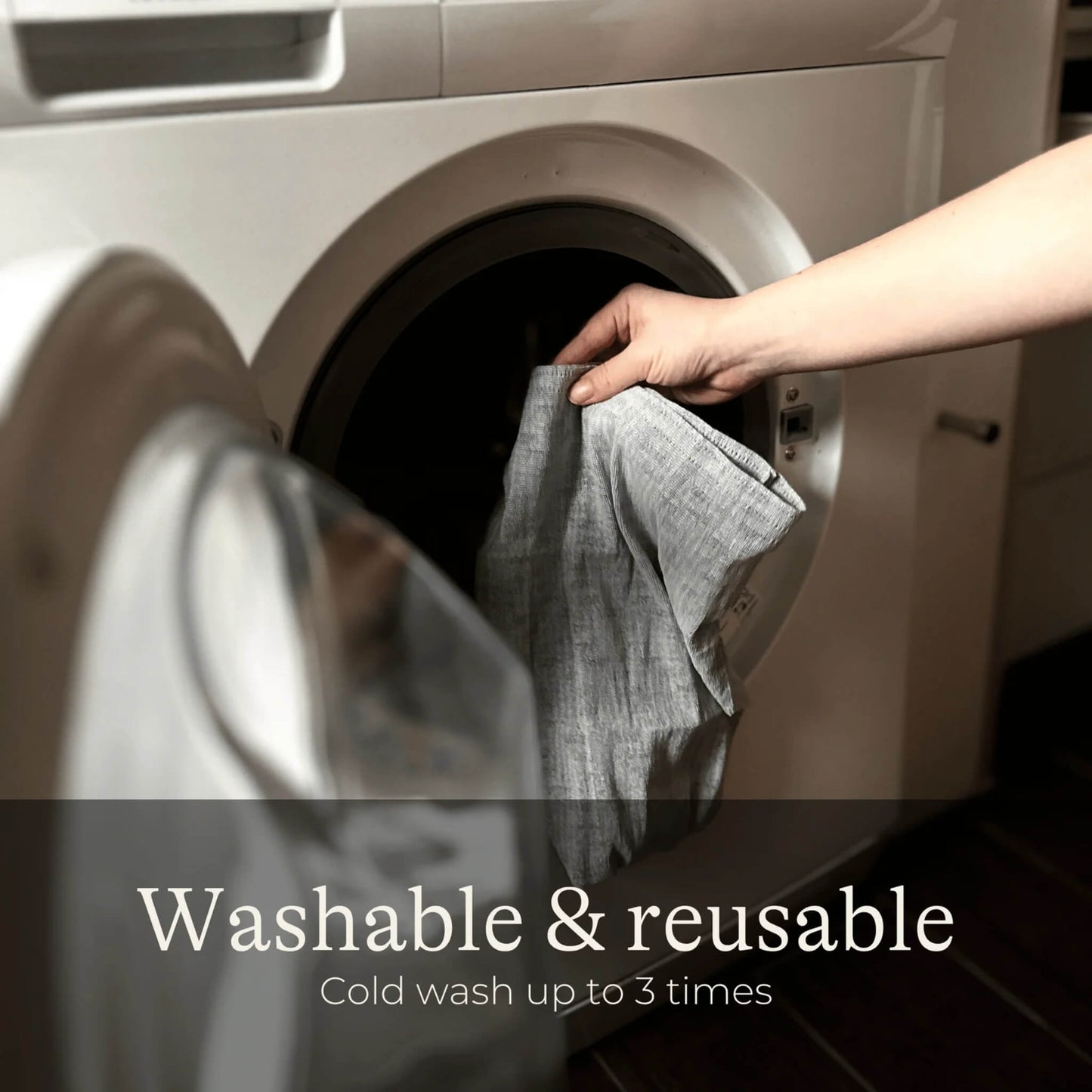 A hand placing grey postpartum underwear into a washing machine, demonstrating the reusable design that can be washed and worn again during postpartum recovery.
