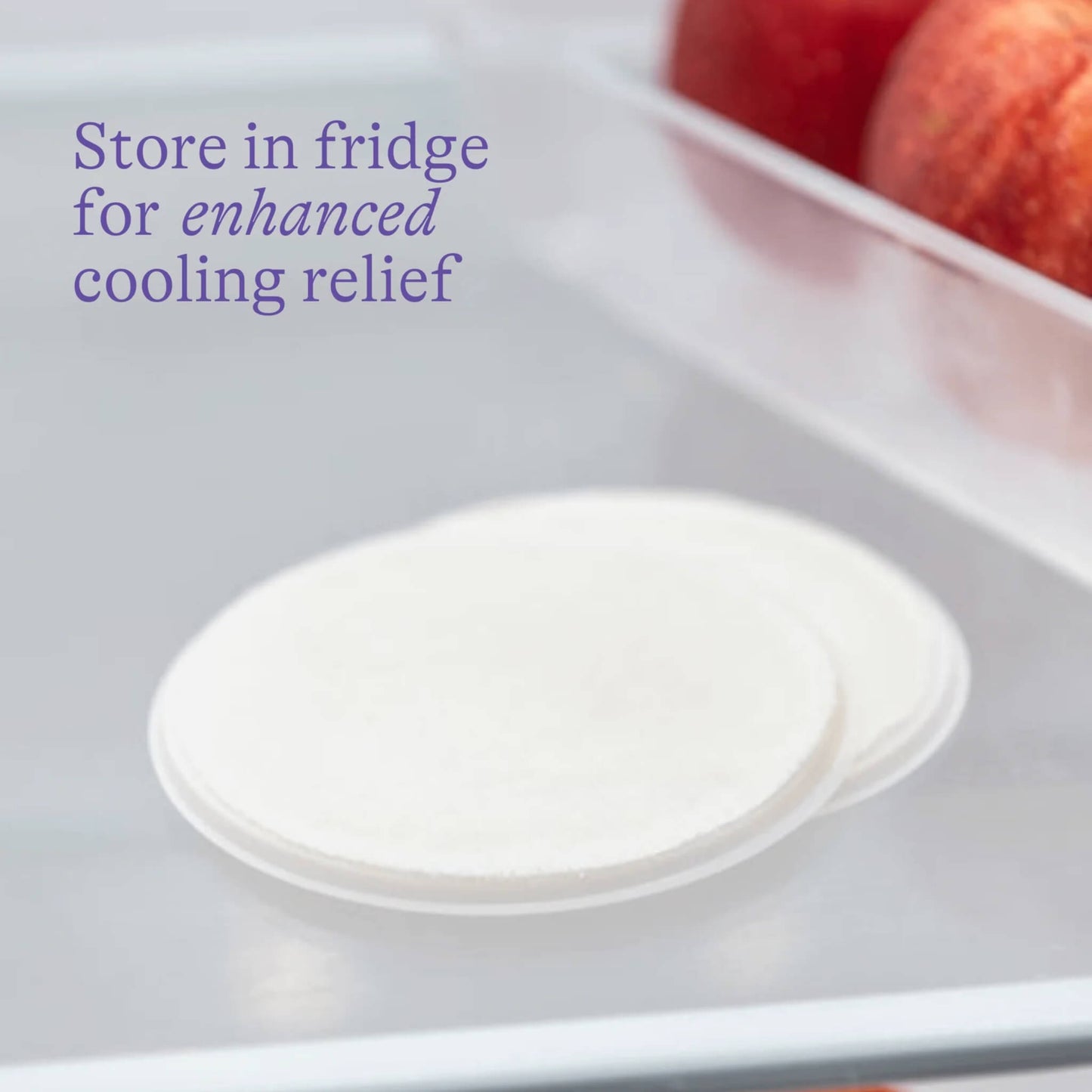 Reusable nipple cooling pads stored in a fridge drawer beside apples, showing how chilling enhances the soothing relief for sore or cracked nipples.