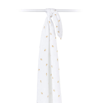 Bee-print cotton muslin swaddle draped over a rod, highlighting the breathable and airy texture of the material.