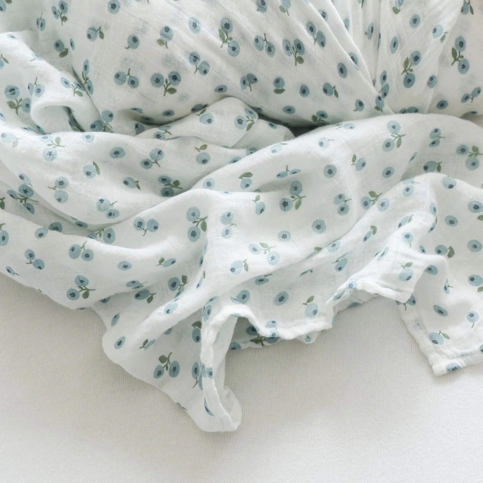Close-up of the soft cotton muslin fabric, showing its loose weave and delicate blue berry design in fine detail.
