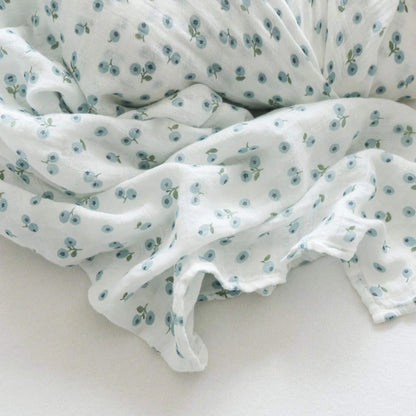 Close-up of the soft cotton muslin fabric, showing its loose weave and delicate blue berry design in fine detail.