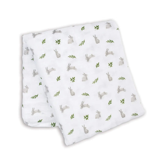 Lightweight muslin swaddle folded flat, showing a repeating pattern of grey bunnies and green leaves across the white cotton fabric.