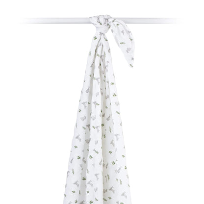 Cotton muslin swaddle draped over a rod, showing its airy, semi-sheer texture and all-over bunny print.