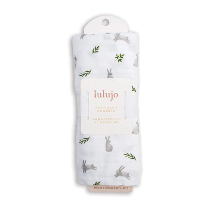 Swaddle rolled in its Lulujo packaging with the label visible, showing the grey bunny and green leaf pattern through the fabric.