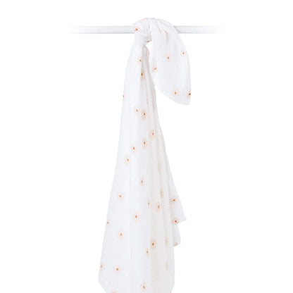 Cotton muslin swaddle draped over a rod, highlighting its airy weave and delicate daisy print.