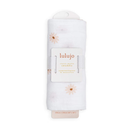 Swaddle rolled in its Lulujo packaging with the label visible, showing the subtle peach daisy design through the folds.