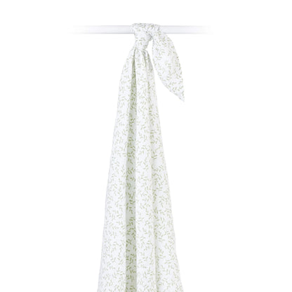Cotton muslin swaddle draped over a rod, highlighting its airy weave and soft botanical design.