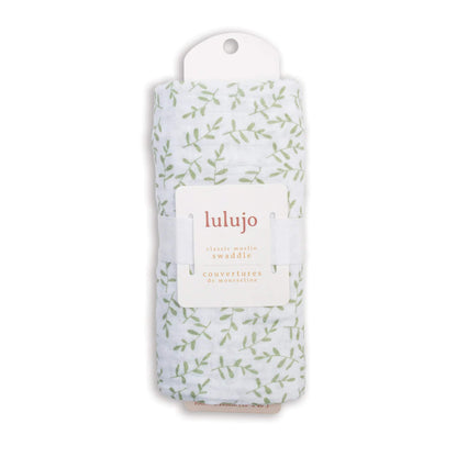 Swaddle rolled in its Lulujo packaging with the label visible, showing the pale green leaf pattern through the fabric.