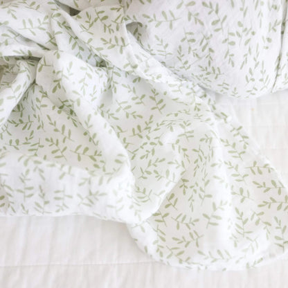 Close-up of the muslin fabric showing the gentle weave and scattered green leaf print.