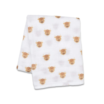 Lightweight muslin swaddle folded flat, showing a repeating pattern of cheerful brown Highland cow illustrations across the white cotton fabric.