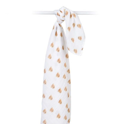 Cotton muslin swaddle draped over a rod, highlighting its airy weave and all-over Highland cow print.
