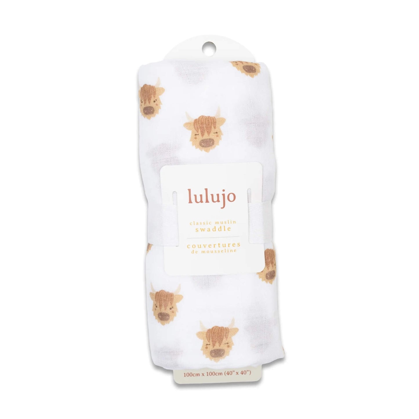 Swaddle rolled in its Lulujo packaging with the label visible, showing the cow motif through the white muslin fabric.