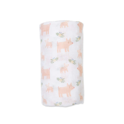 Lulujo Cotton Muslin Swaddle in the Piggy design, neatly rolled to show its soft white fabric decorated with pale pink pig illustrations and small green floral accents.